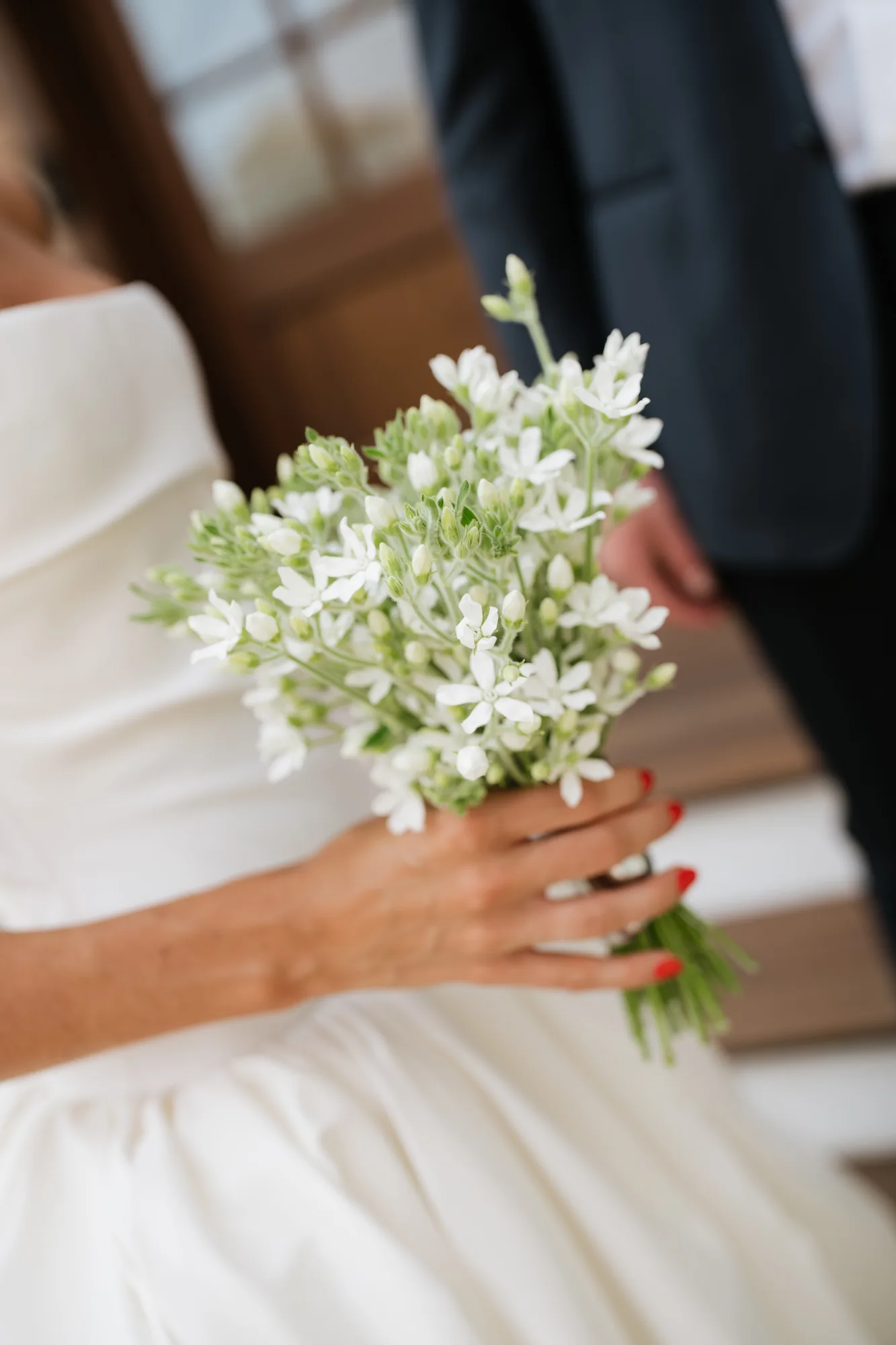 Lindsey holds a petite bouquet of white star-shaped tweedia, pale green buds loose among the blooms