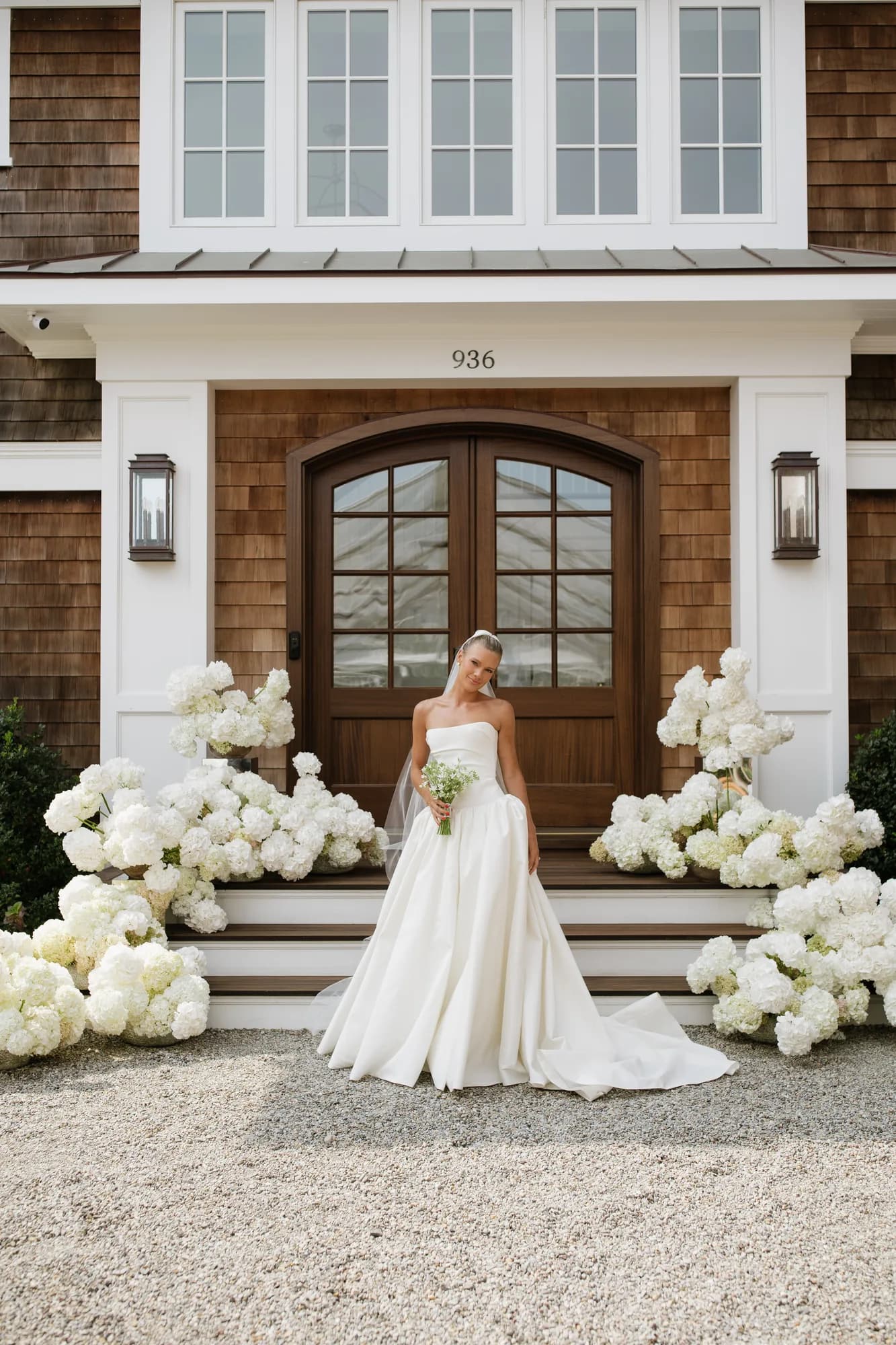 Lindsey stands centered before the front steps, white hydrangea massed like clouds along both sides