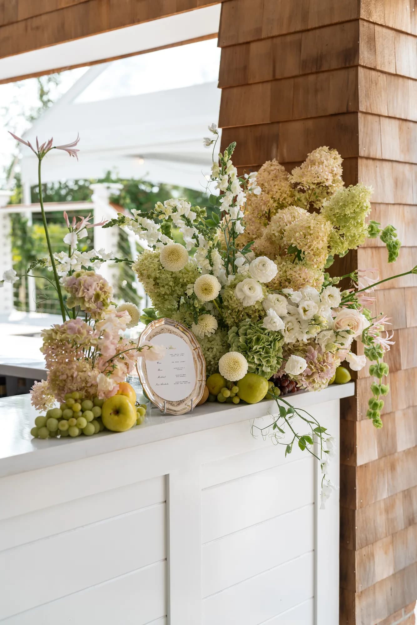 The bar arrangement in blush and chartreuse: limelight hydrangea, snapdragon, ranunculus, nerine and fruit