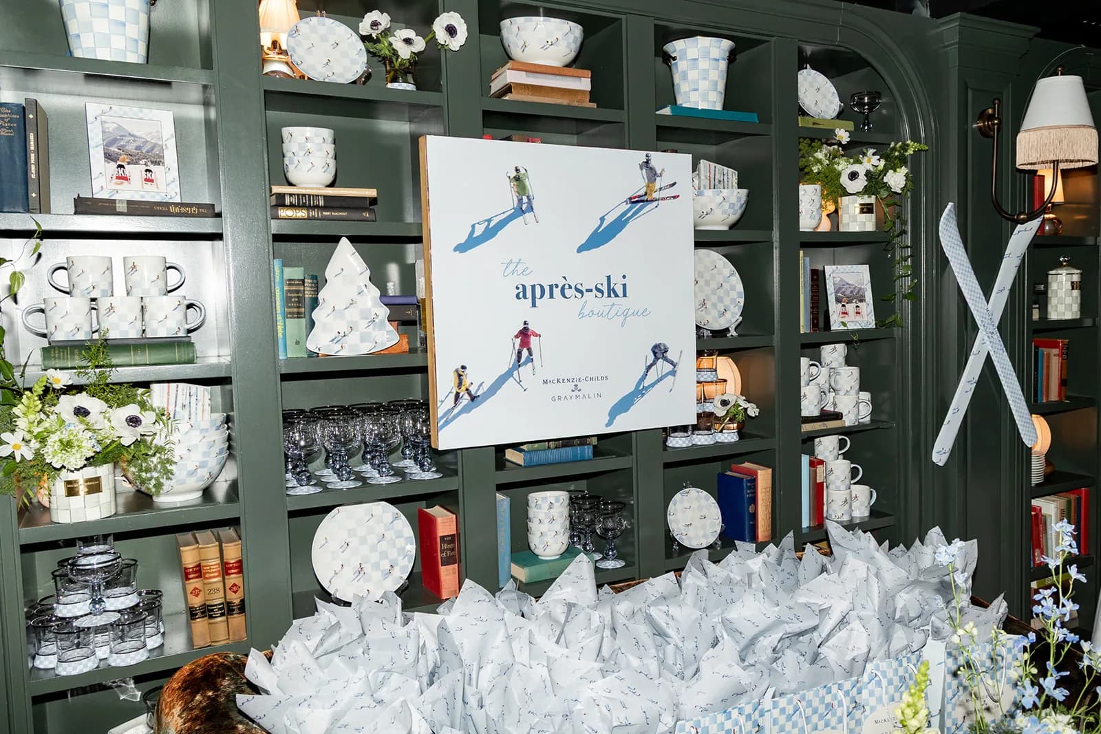 Small white arrangements tucked among ski-print ceramics and books on green shelves beside the après-ski boutique sign
