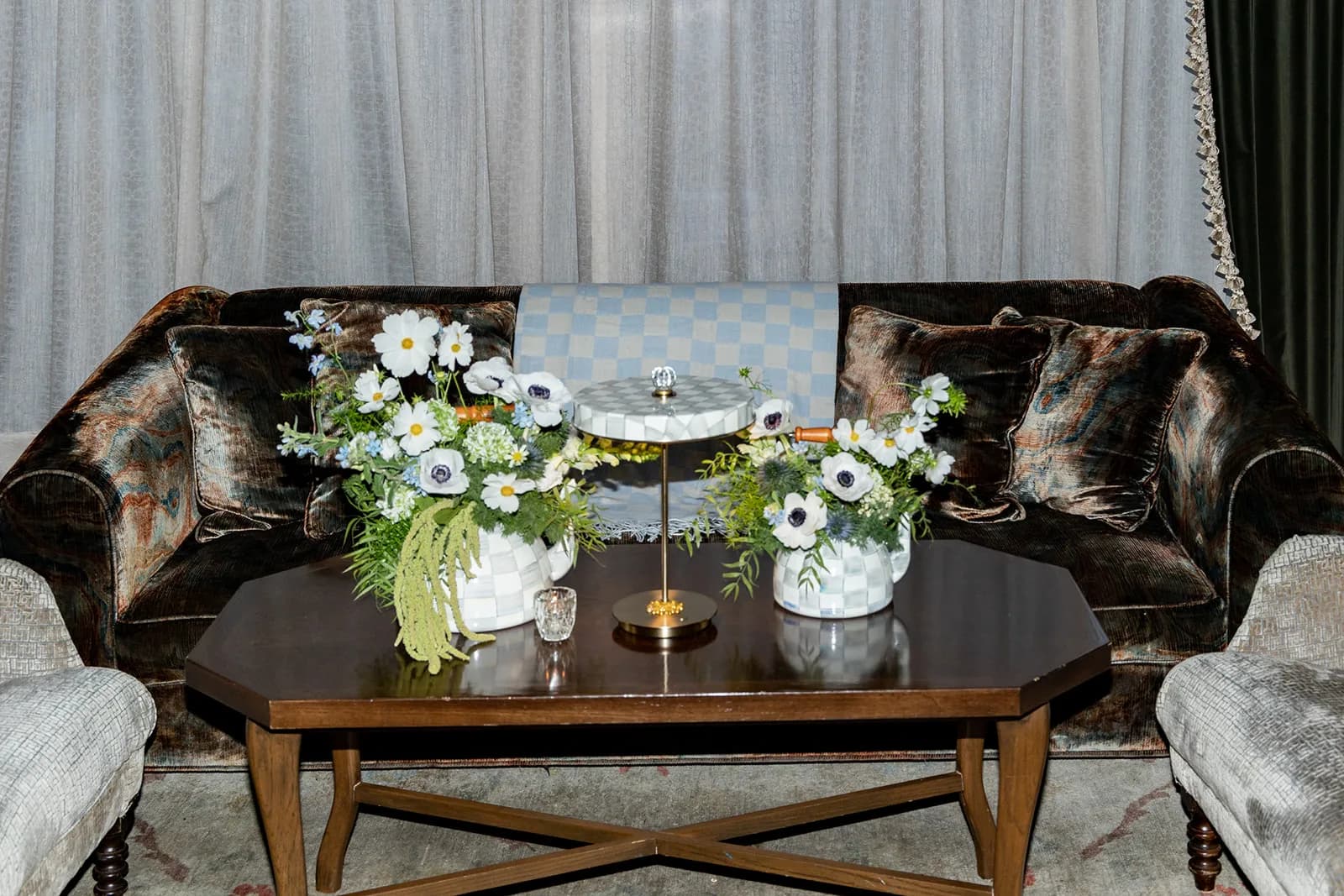 White cosmos, anemones and trailing green amaranthus in two MacKenzie-Childs check pots on a dark wood coffee table