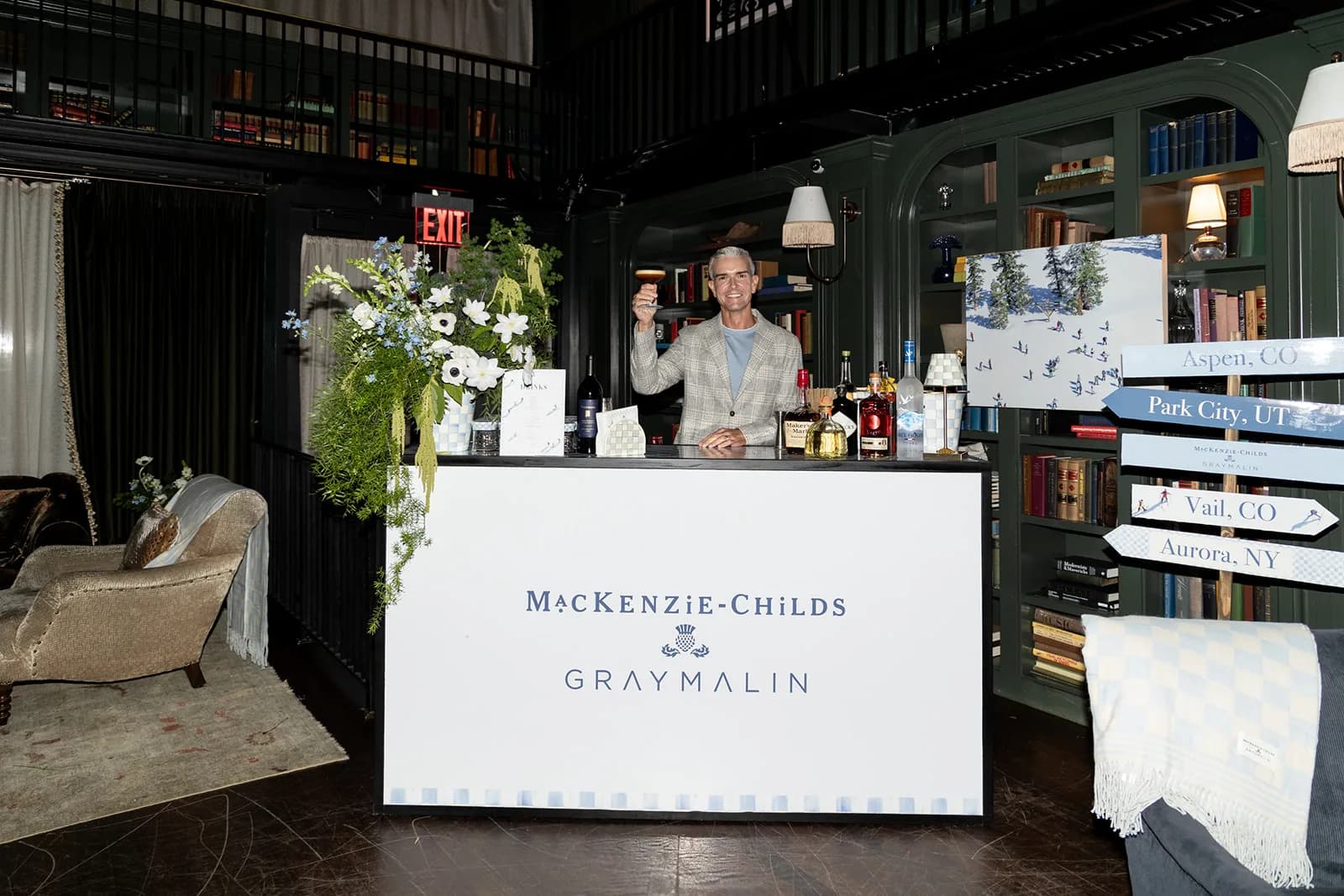 A cascading arrangement of anemones, delphinium and trailing greenery spills from the corner of the branded cocktail bar