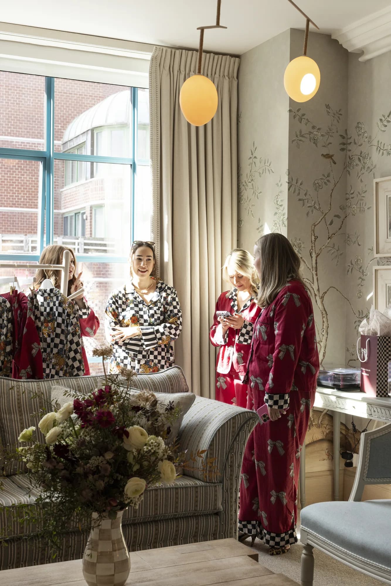 Guests in Printfresh pajamas talk by a rolling rack as a loose arrangement of ranunculus and cosmos fills the foreground