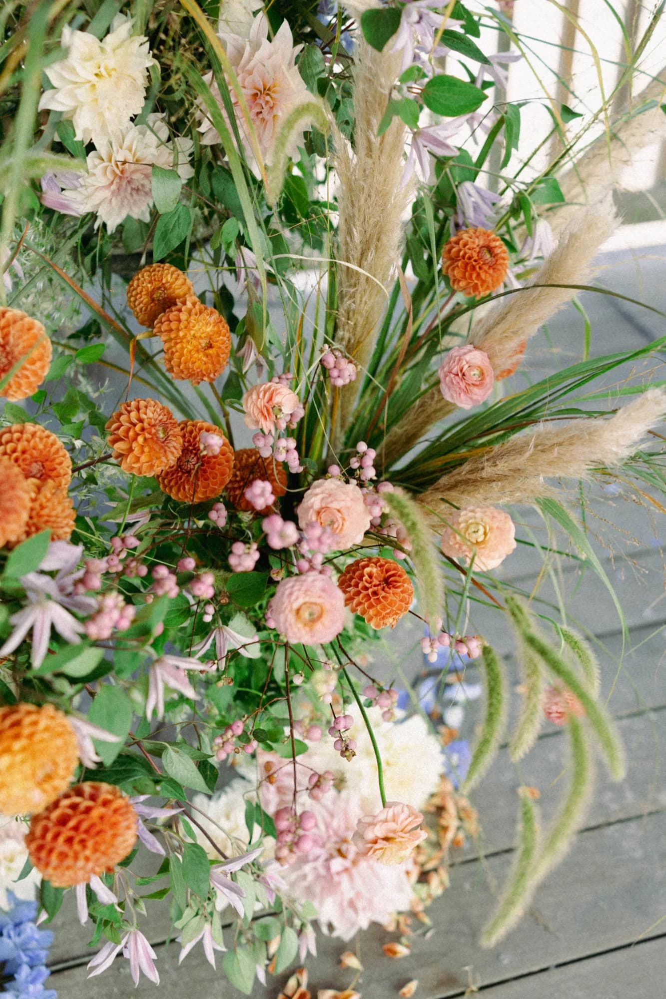 Overhead view of a ceremony arrangement with orange dahlias, cream dinnerplate dahlias, snowberry and pampas grass